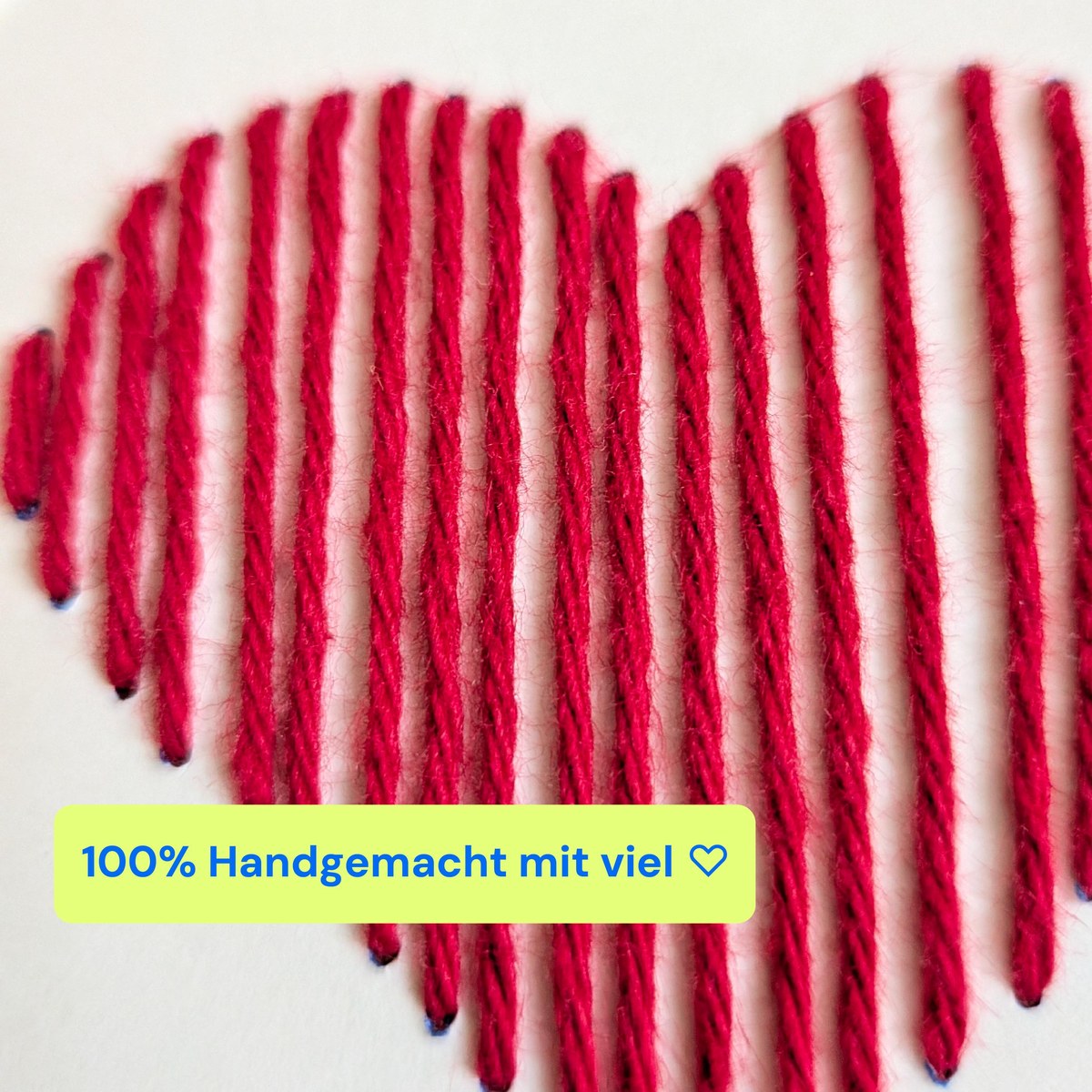 Nahaufnahme eines von Hand gestickten Herzens aus rotem Garn